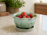 Green handmade pottery berry bowl filled with strawberries on kitchen counter