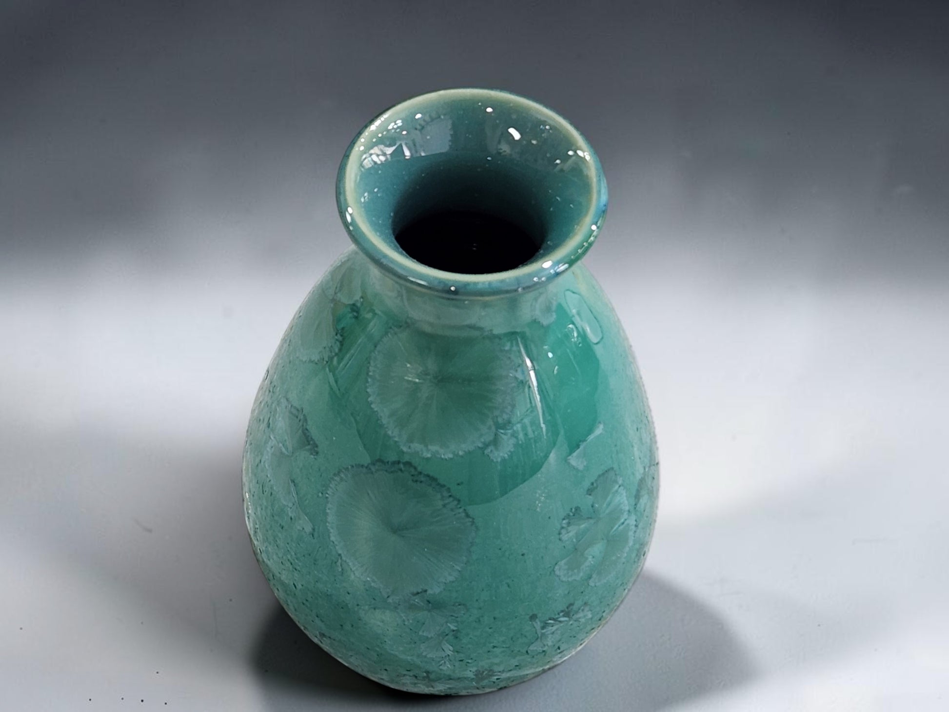 Green pottery vase with rounded body and softly flared opening