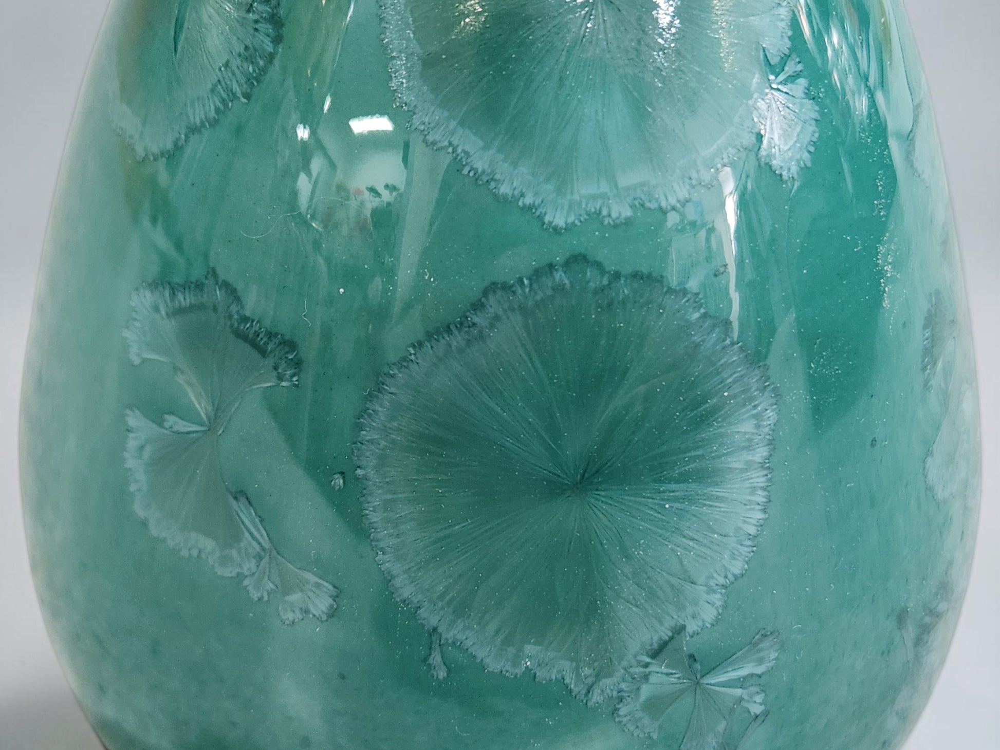 Close-up of naturally formed crystal patterns on a green porcelain vase
