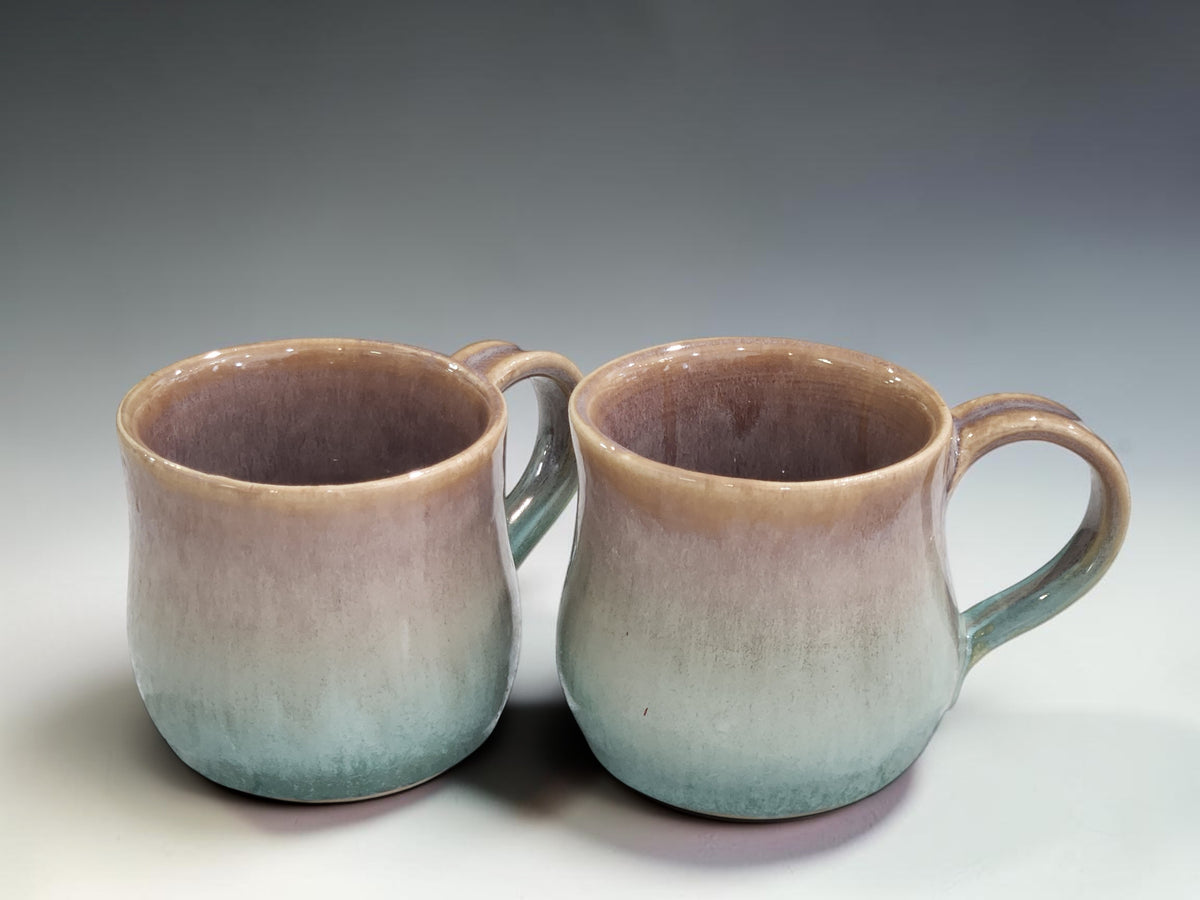 Handmade stoneware coffee mug with mottled brown and green glaze created through layered ceramic glazing techniques.