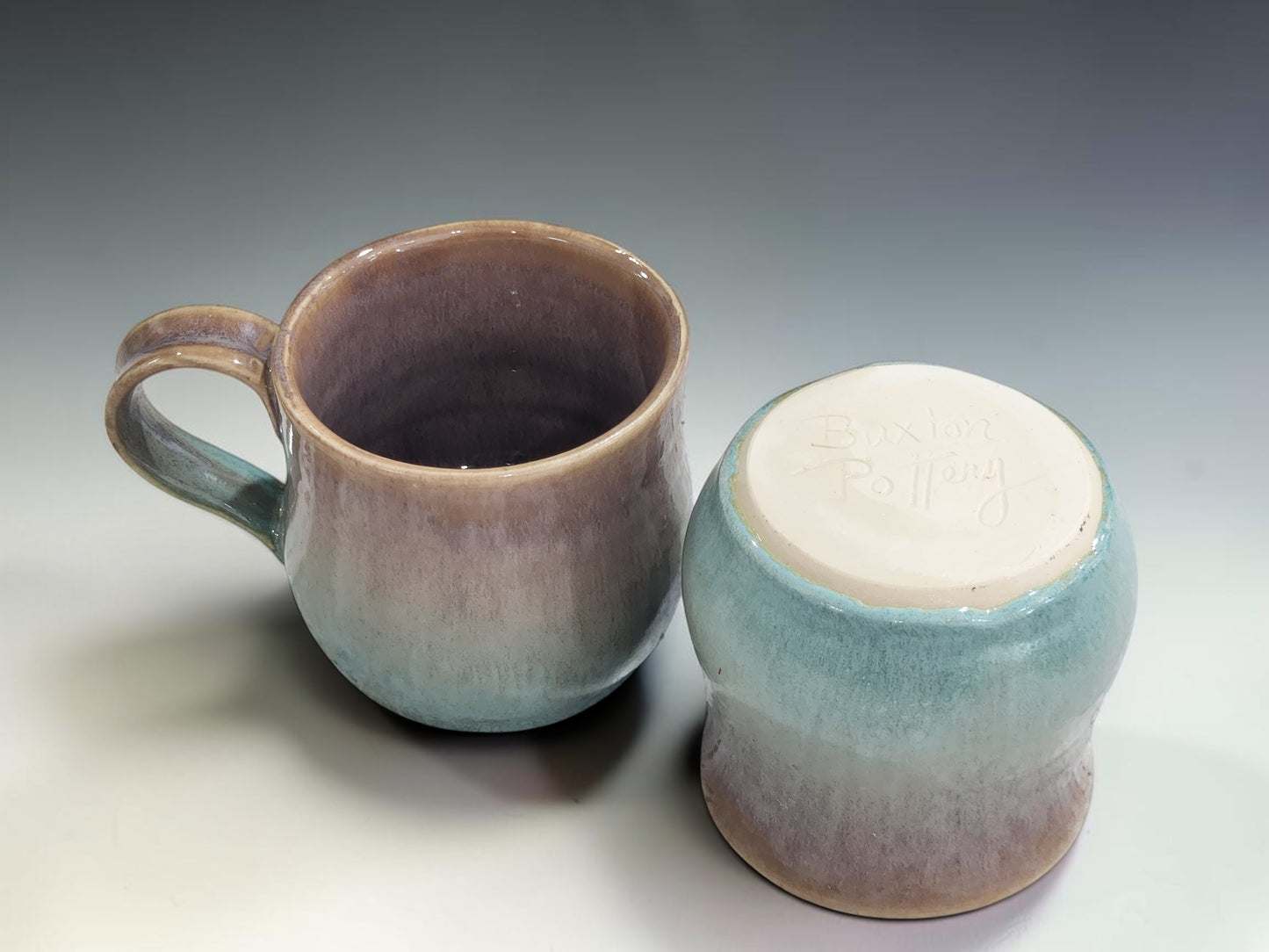 Pair of handmade pottery mugs with matching mottled brown and green glaze effects created using layered glazes.