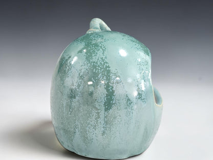 Side view of rounded green pottery salt pig with accessible front opening
