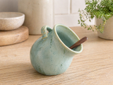 Handmade green ceramic salt pig on a light timber kitchen bench in a styled kitchen setting