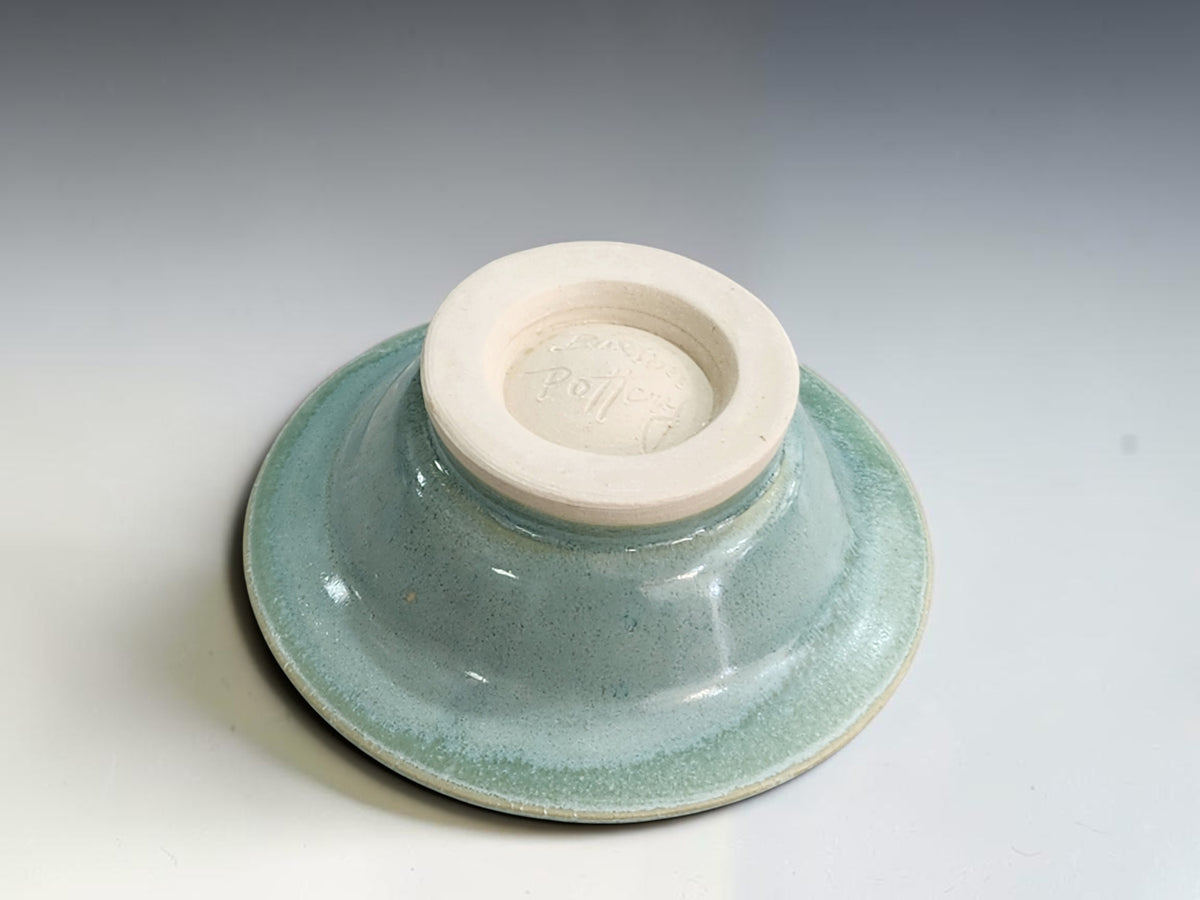 Close-up of the bottom of the  mottled blue-green glaze inside a handmade ceramic jewellery bowl.