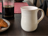 Handmade white crystalline pottery mug on wooden table