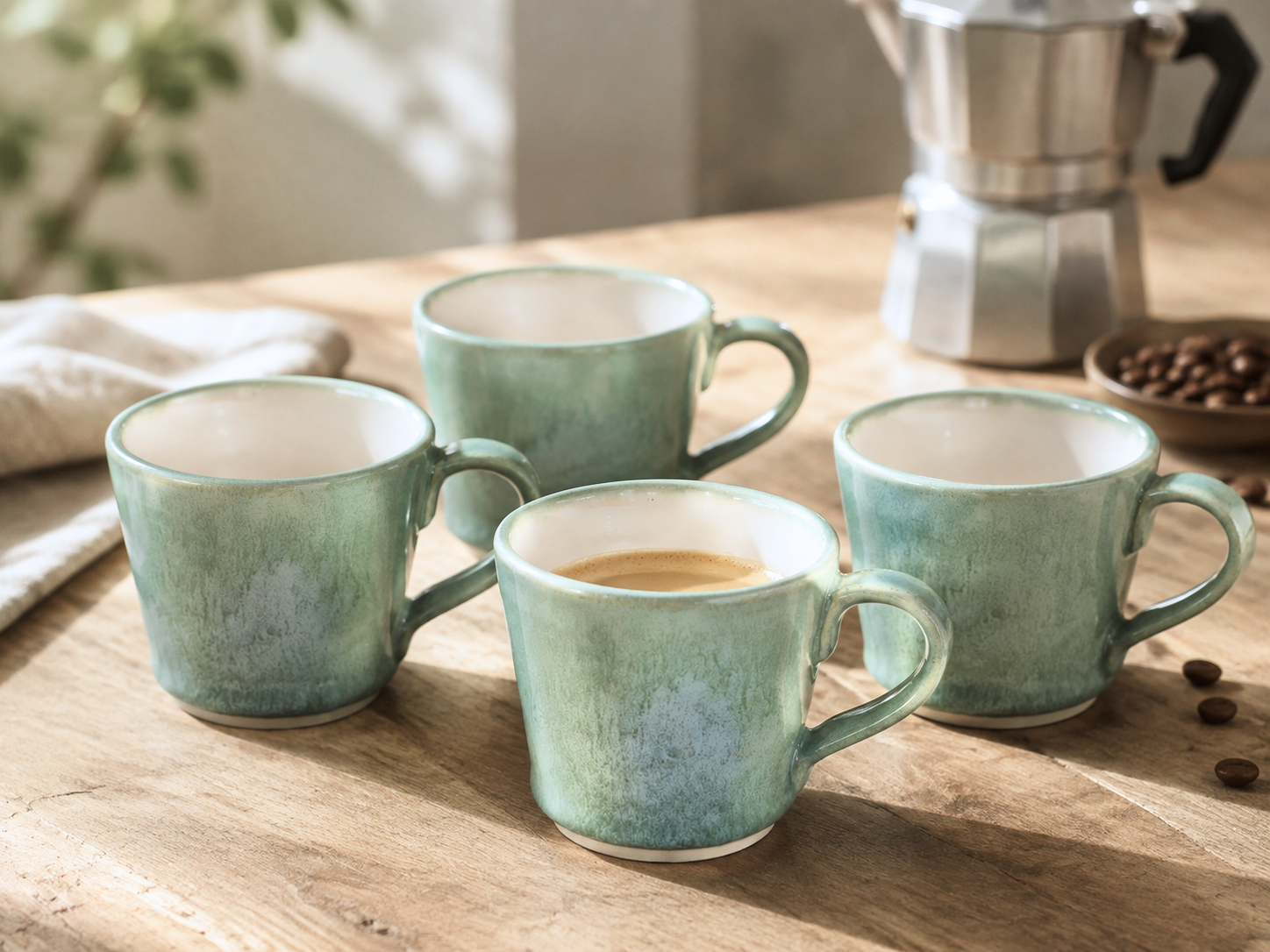 Set of four handmade green espresso cups with coffee maker on timber table