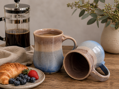 Hero image of two handmade 500ml ceramic mugs in oatmeal brown and blue glaze by Buxton Pottery