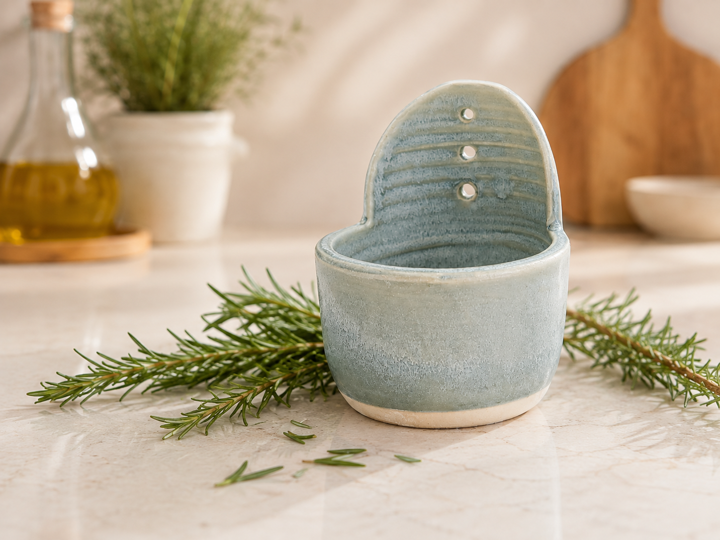 Handmade ceramic herb stripper in soft blue-grey glaze styled with fresh rosemary in a warm kitchen setting