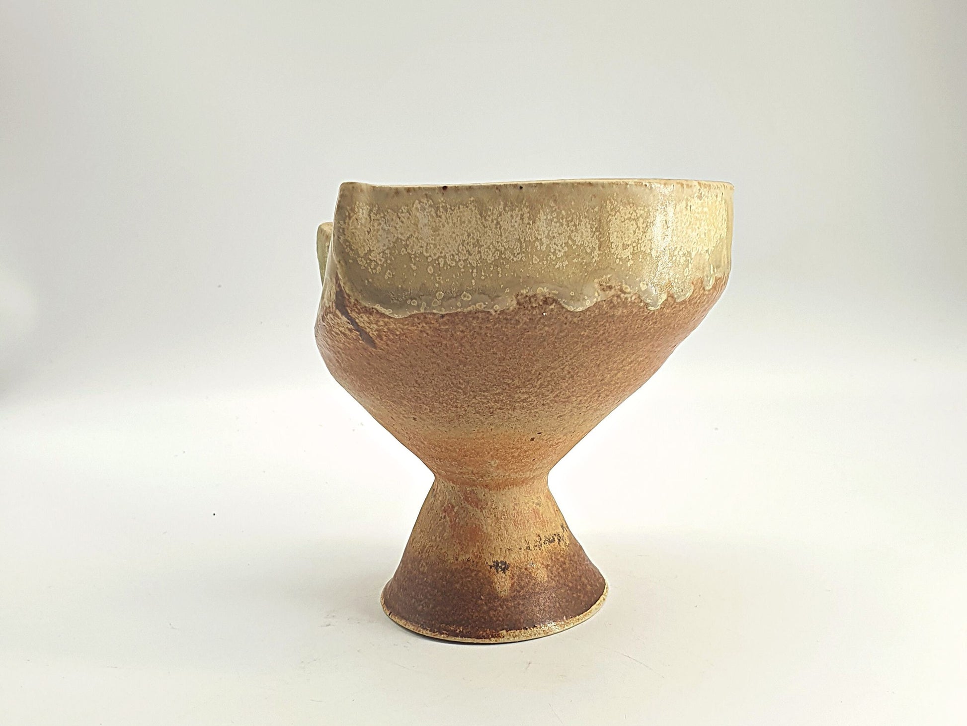 Organic-formed bowl with a slanted, asymmetrical rim and a raised foot.