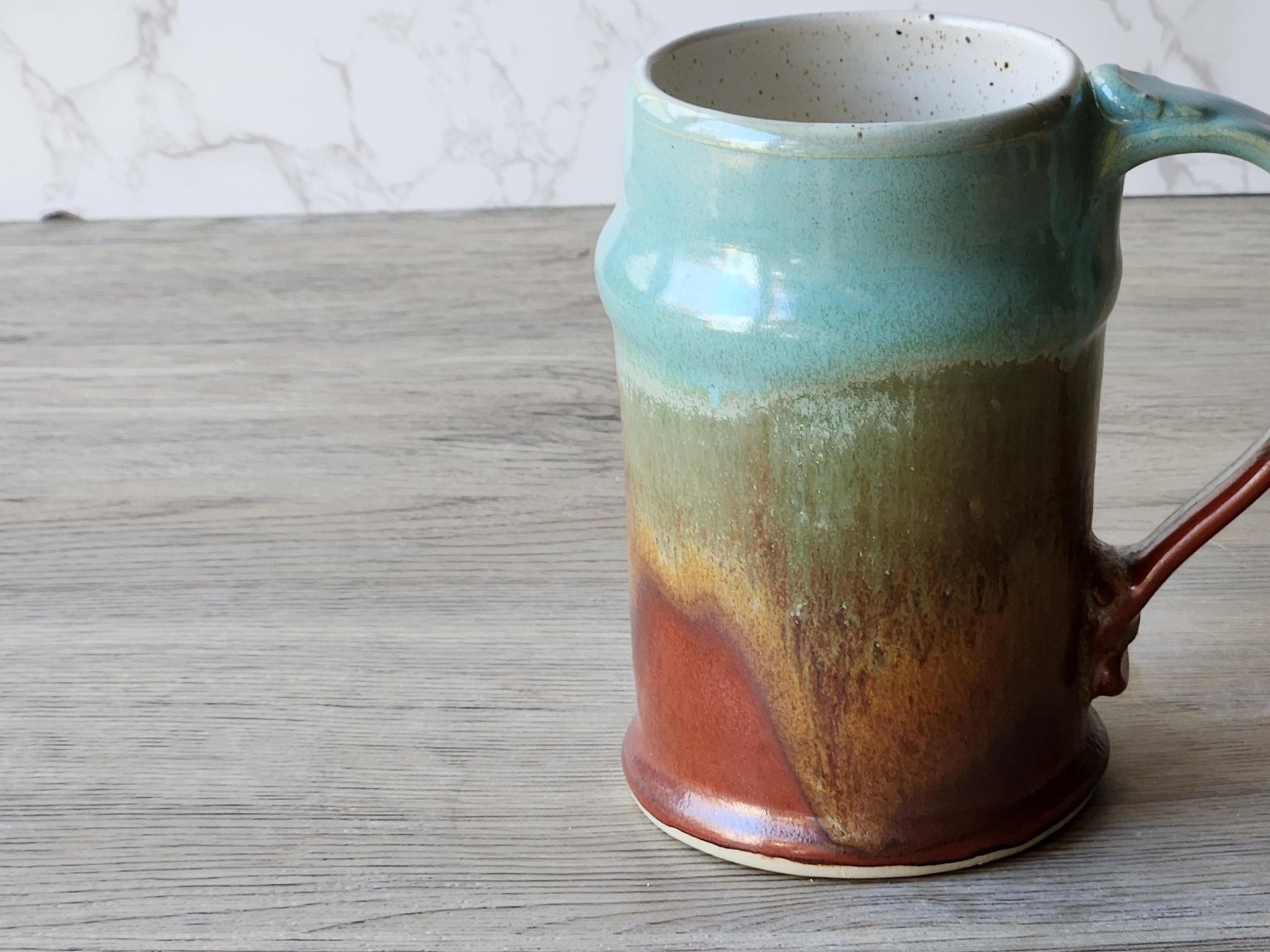 Side view of wheel-thrown stoneware beer mug with mottled earth-tone finish