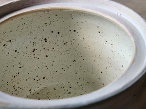 Close up of specked cream glaze on the inside of the handmade ceramic lidded pot.