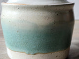 Close up of the green and speckled cream glaze on the handcrafted pottery jar.