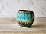 Wheel-thrown yunomi pottery cup in moss green, brown, burgundy and turquoise glazes.