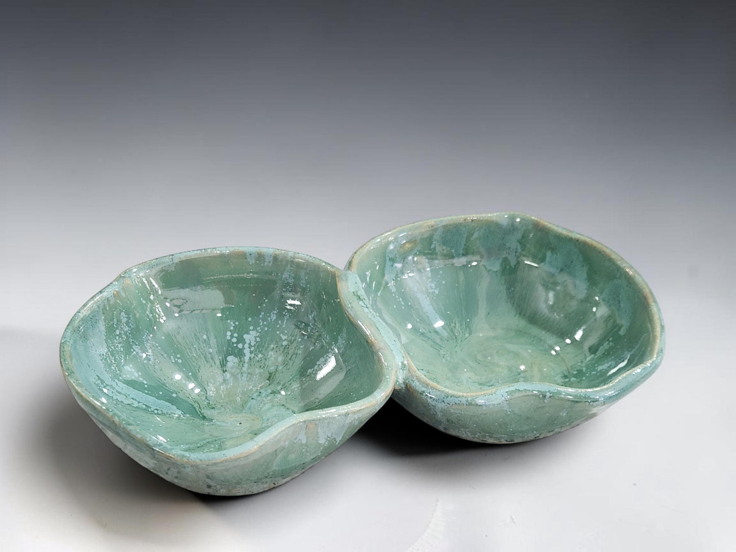 Wheel-thrown ceramic double bowl in a soft mottled green glaze, handcrafted in Melbourne using traditional pottery techniques.