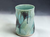 Handmade ceramic coffee mug in Bush Creek glaze, photographed on a professional grey gradient studio background