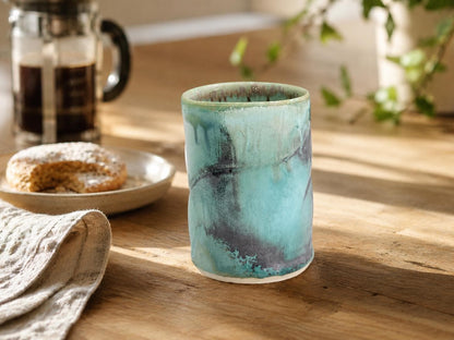 Handmade ceramic 250ml tumbler in turquoise green glaze styled with coffee and pastry in a warm kitchen setting