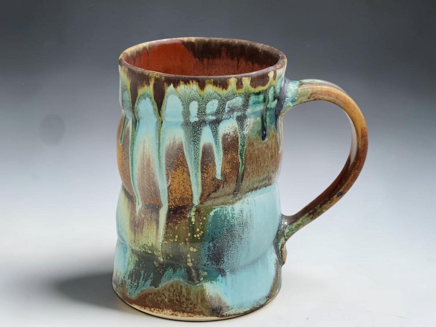 Australian handmade pottery mug with rustic turquoise, brown and rust glaze movement