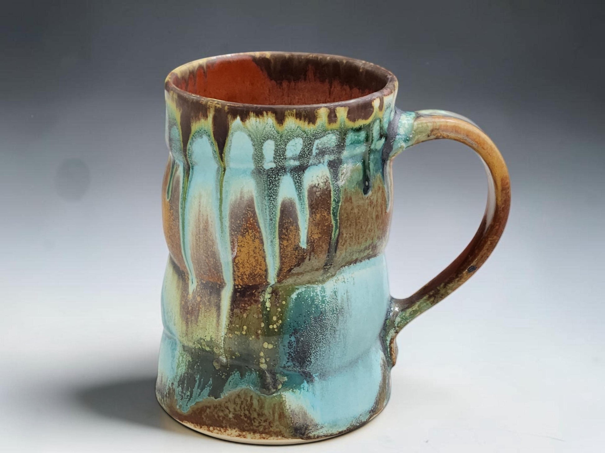 Australian handmade pottery mug with rustic turquoise, brown and rust glaze movement