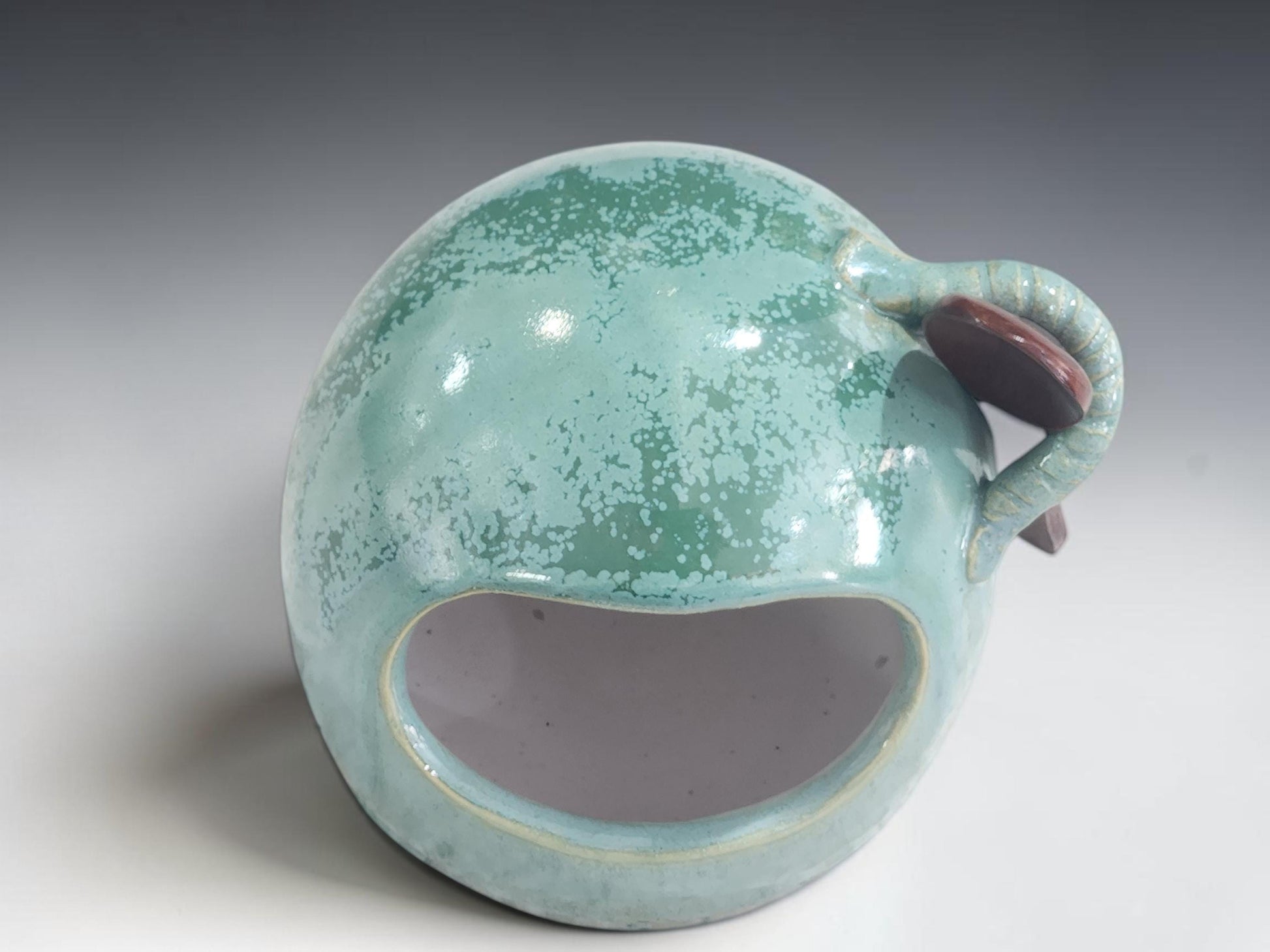 Mottled green ceramic salt cellar filled with coarse sea salt on a timber bench
