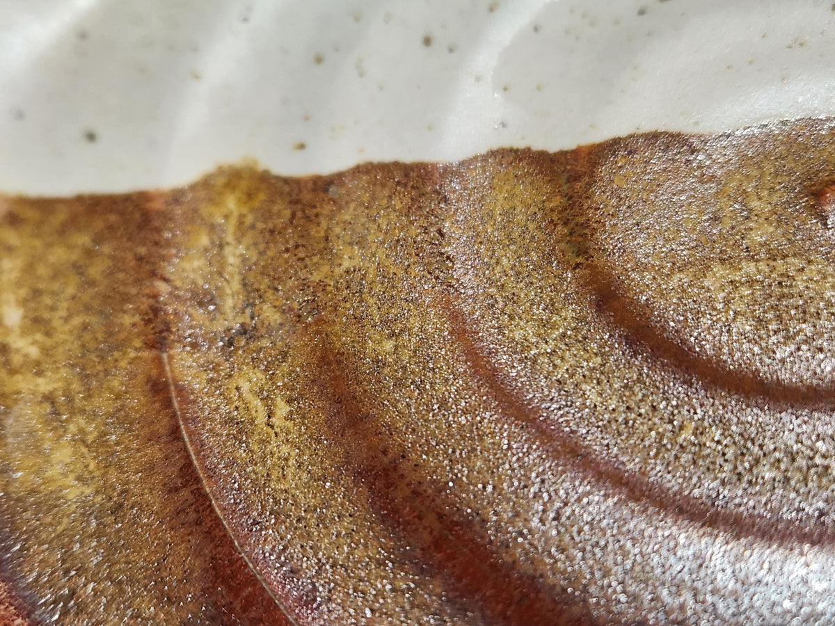 Close-up of cream and brown glaze on handmade ceramic spoon rest