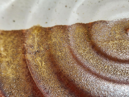 Close-up of cream and brown glaze on handmade ceramic spoon rest