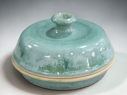 Close up of sage green handmade pottery glaze on ceramic lidded serving bowl showing mottled glaze detail