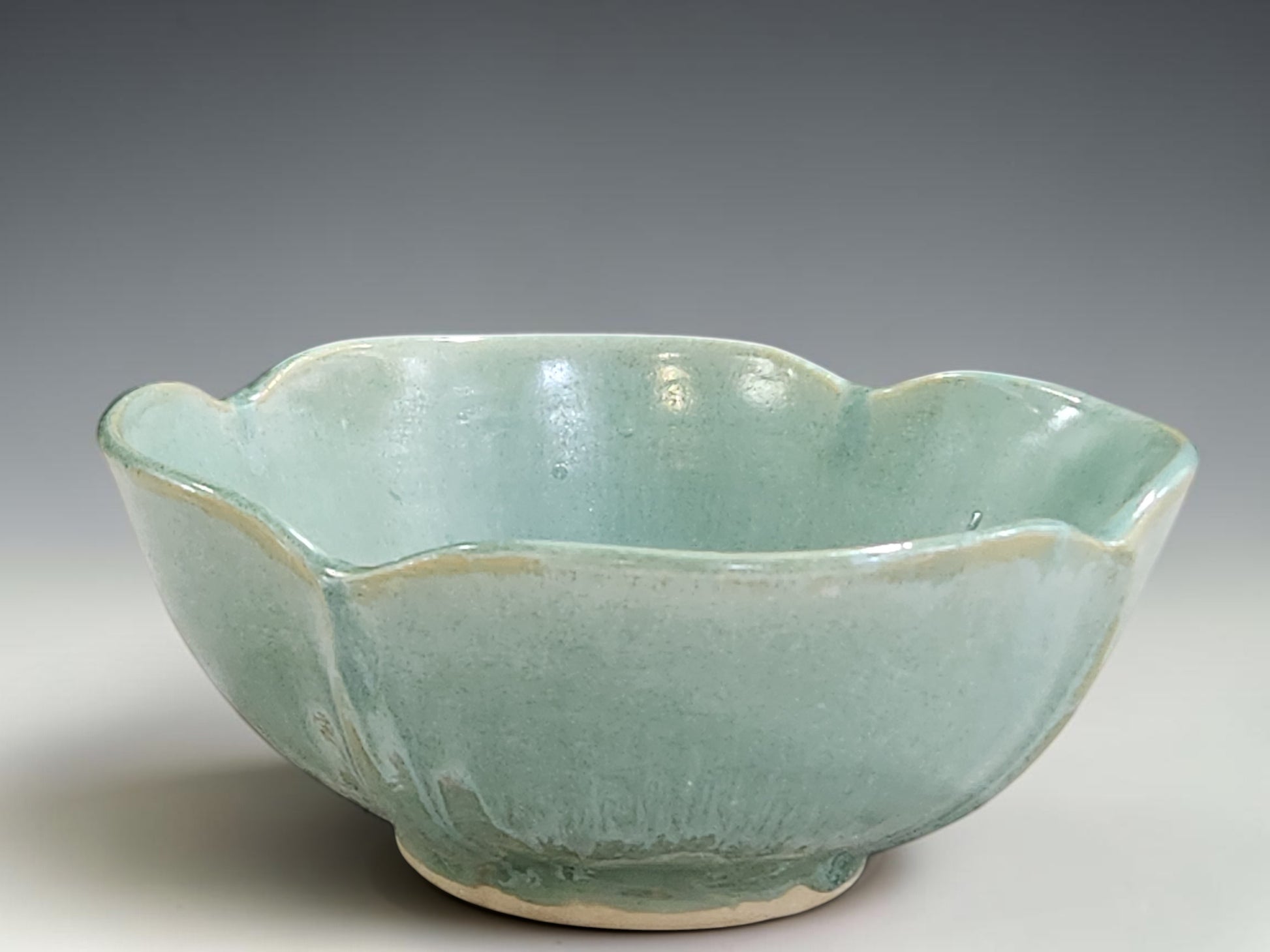 Handmade pottery bowl with organic altered rim and soft glossy green glaze
