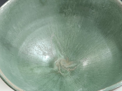 Close-up of handmade ceramic bowl showing layered seafoam green glaze and soft rim detail