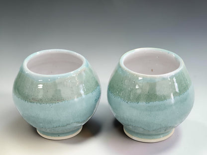 Pair of handmade ceramic teacups with mottled green glaze, crafted by Buxton Pottery using traditional stoneware pottery techniques in Melbourne.