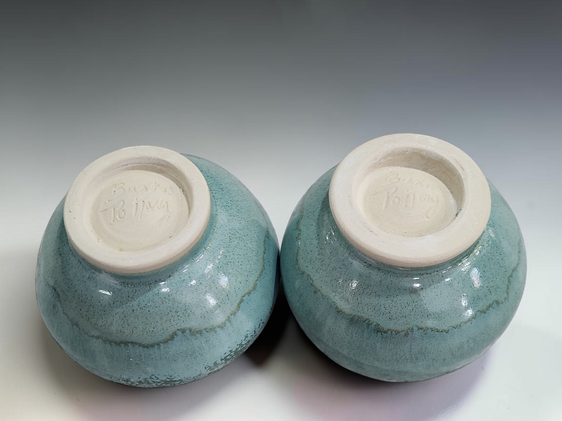 Handmade stoneware teacups in a calming tea ceremony-inspired setting, featuring Buxton Pottery's signature mottled green glaze and contemporary artisan design.