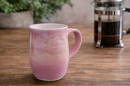 Pink handmade pottery mug on timber benchtop with French coffee plunger