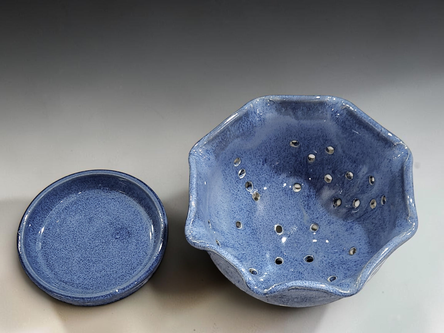 Handmade ceramic berry bowl with drainage holes and matching saucer in blue glaze