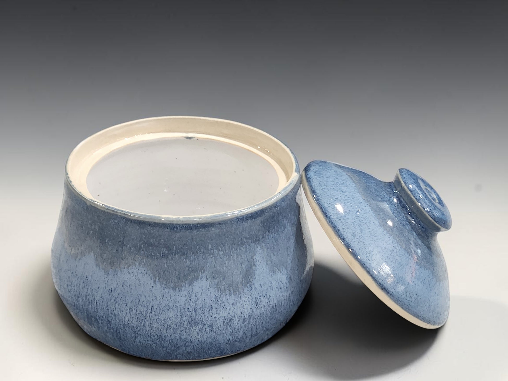 Blue pottery sugar bowl with rounded shape and fitted lid