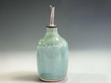 Handmade pottery oil bottle with pourer in a soft mottled green glaze, crafted by Buxton Pottery in Melbourne for storing and serving olive oil.