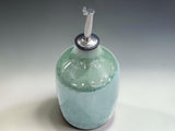 Handcrafted stoneware oil bottle by Buxton Pottery, 400ml capacity with stainless steel pour spout and unique green glazed finish.