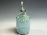 Wheel-thrown ceramic oil cruet in mottled green stoneware, handmade in Melbourne and designed for everyday cooking and kitchen styling.