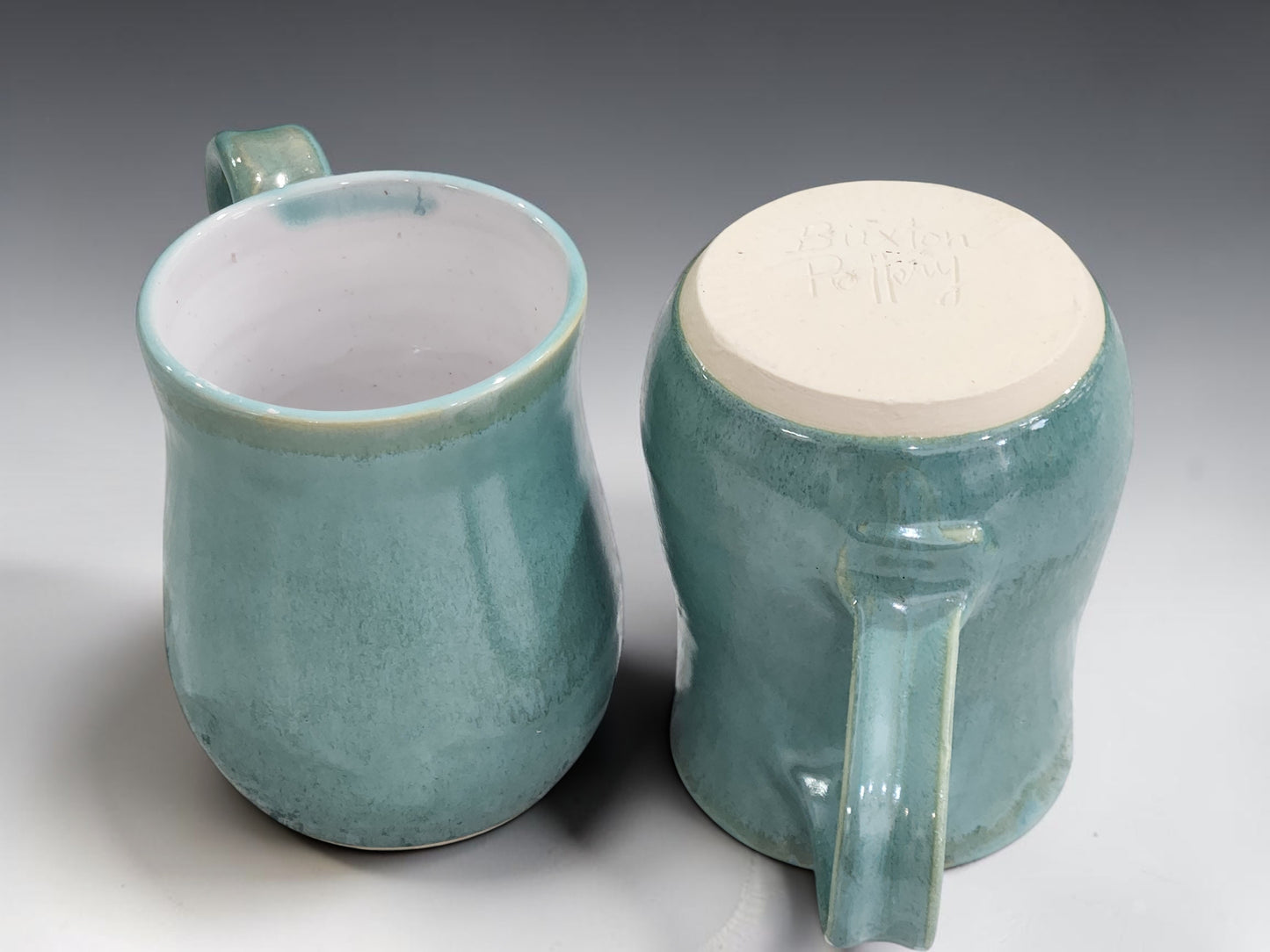 Handcrafted ceramic coffee cup with white glazed interior and organic green exterior, made in Melbourne using traditional pottery techniques.