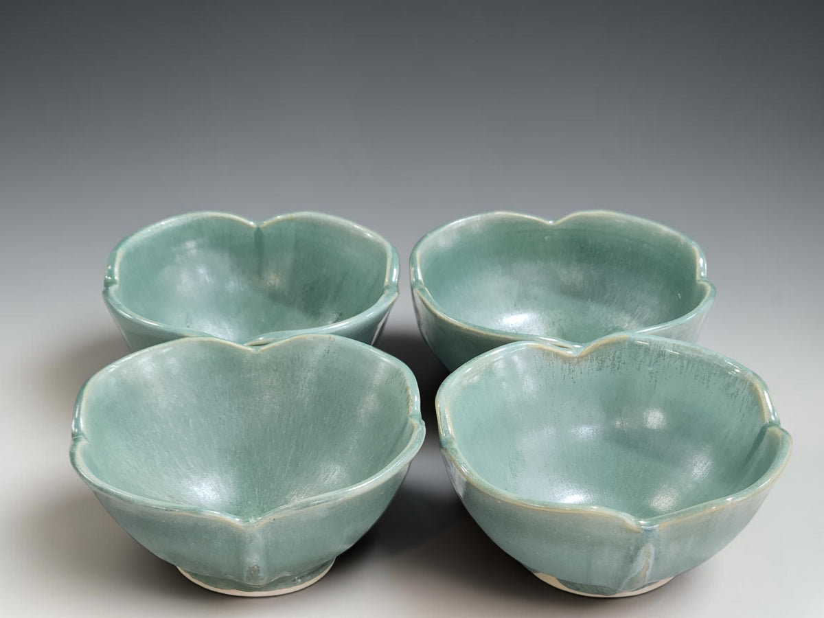 Set of handmade pottery bowls with organic petal-shaped rims and soft green glaze variation