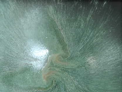 Close-up of handmade ceramic bowl showing layered seafoam green glaze and soft altered rim detail