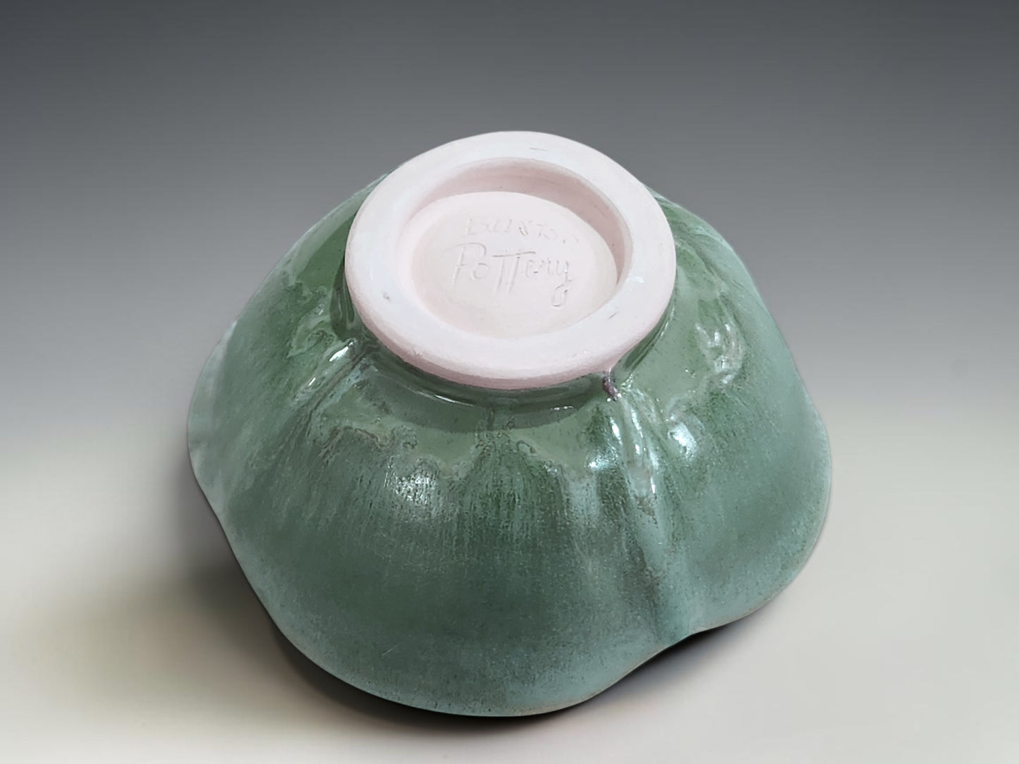 Handmade altered stoneware bowl with glossy green interior and unique handmade finish  showing the bottom with the makers mark