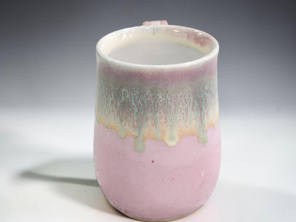 Handmade ceramic mug with soft pink glaze and green drip glaze detail