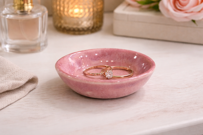 Pink handmade ceramic ring dish with gold rings on dressing table