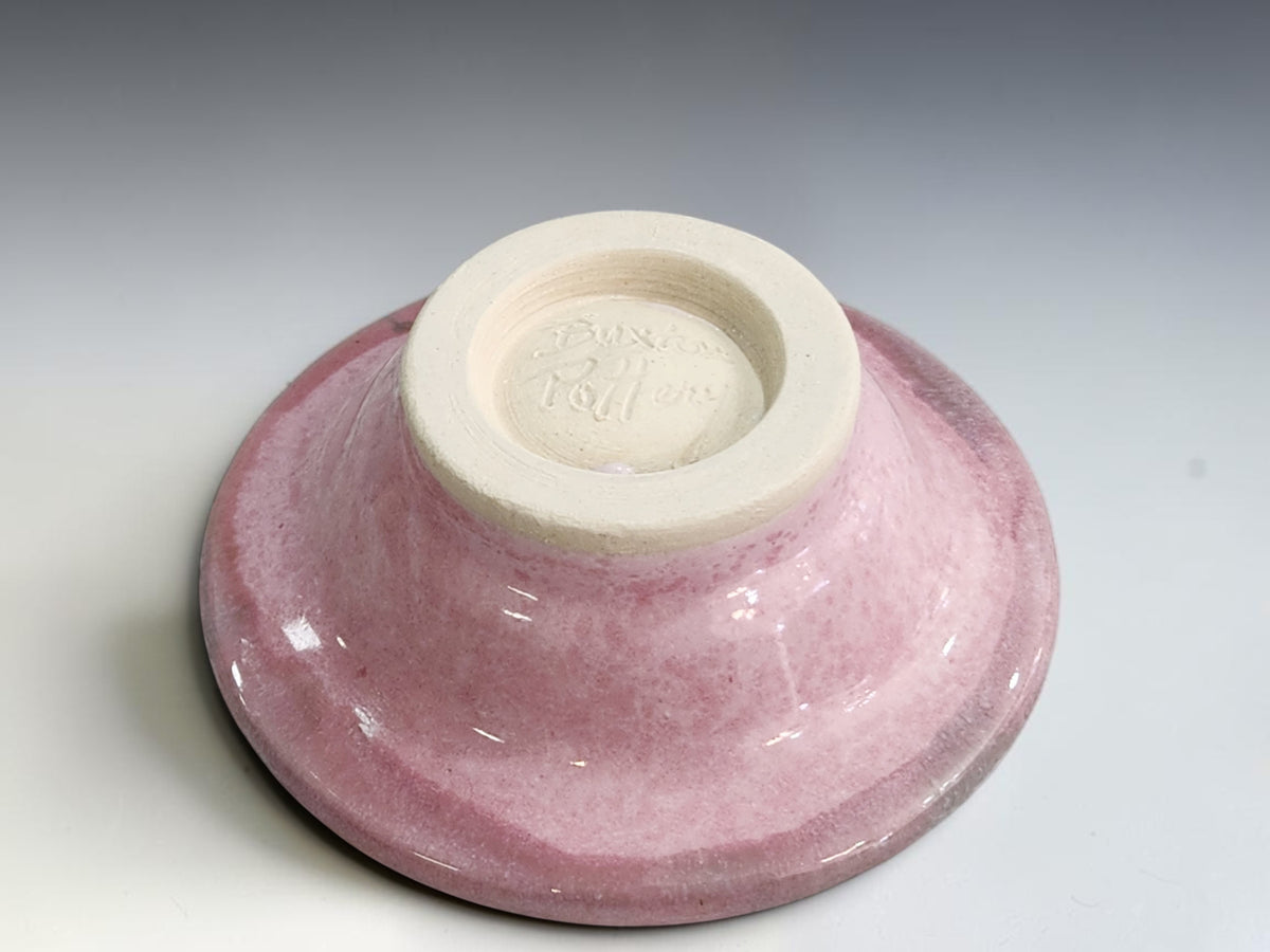 Small handcrafted ring dish with glossy blush pink glaze and dark green-grey accents.