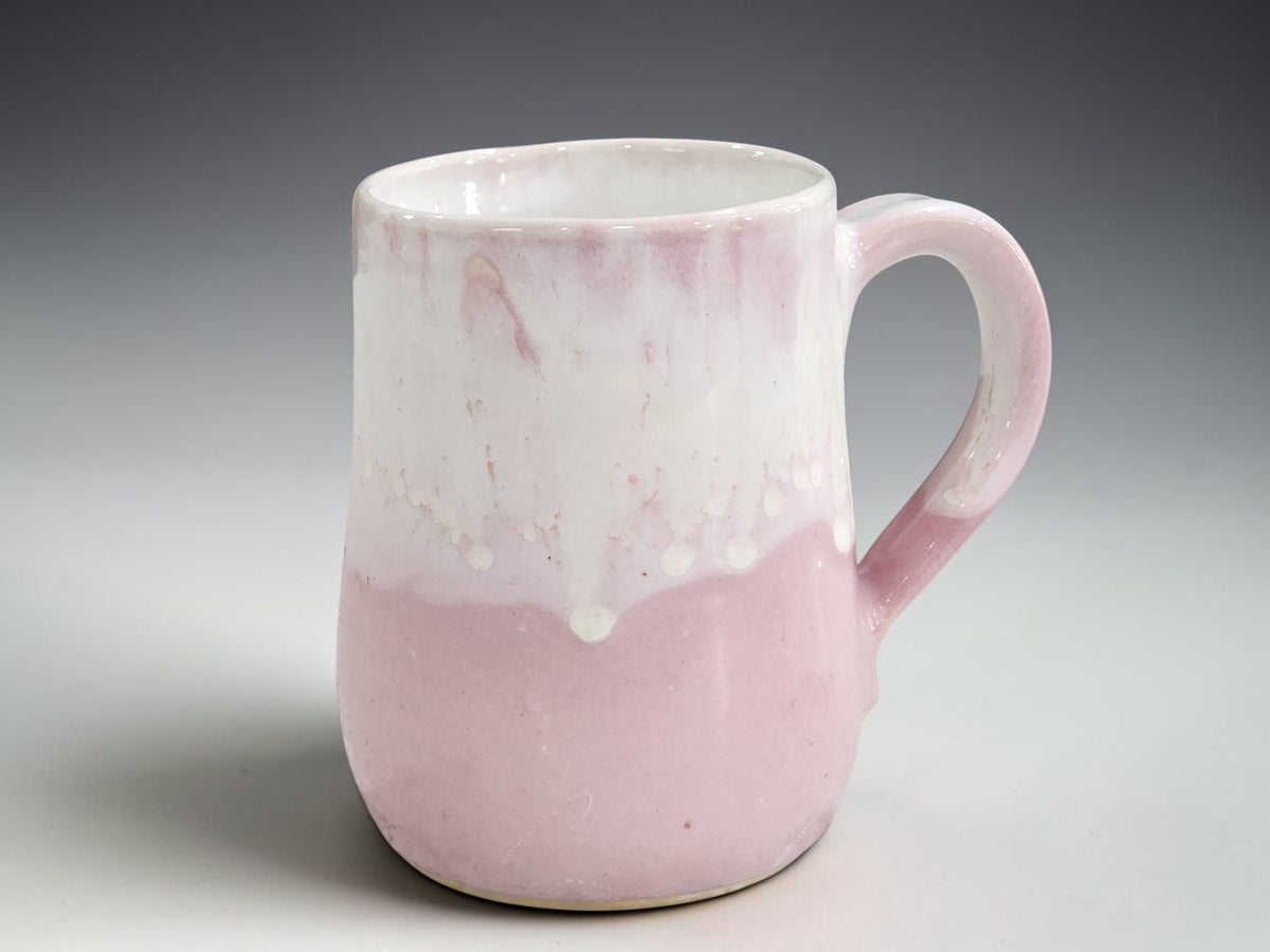 Soft pink handmade pottery mug with flowing creamy white glaze