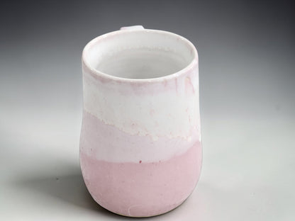 Handmade pink ceramic mug showing natural cream glaze movement