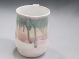 Handmade pottery mug with blush pink glaze and green accents