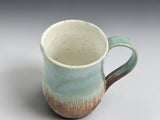 Tall pottery mug with rustic earthy tones and glossy finish