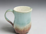 Handmade tea mug with curved handle and flowing glaze