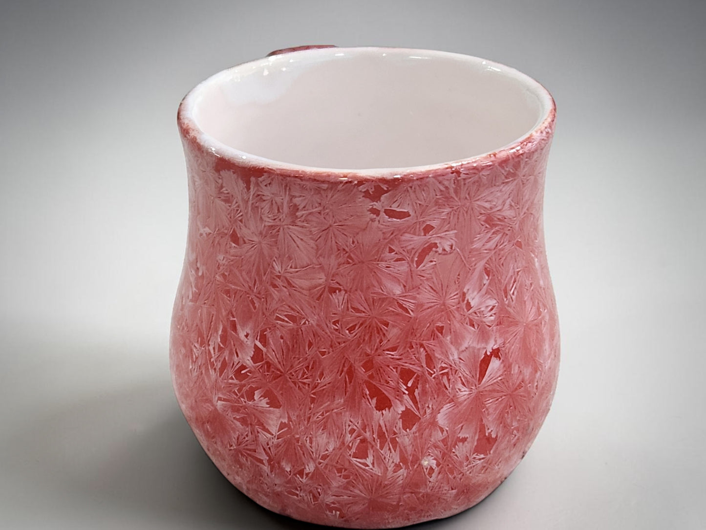 Side view of red crystalline porcelain mug showing its rounded form