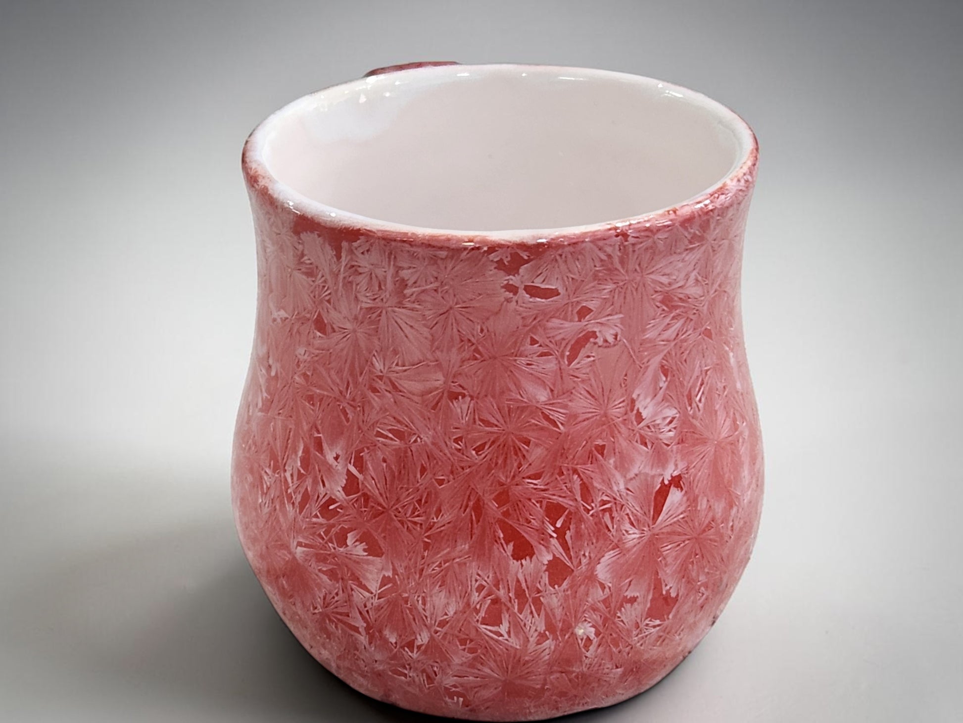 Side view of red crystalline porcelain mug showing its rounded form